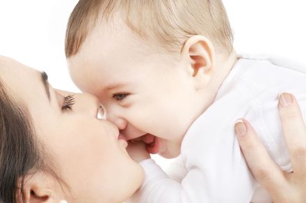 Close up of a mother kissing her smiling baby